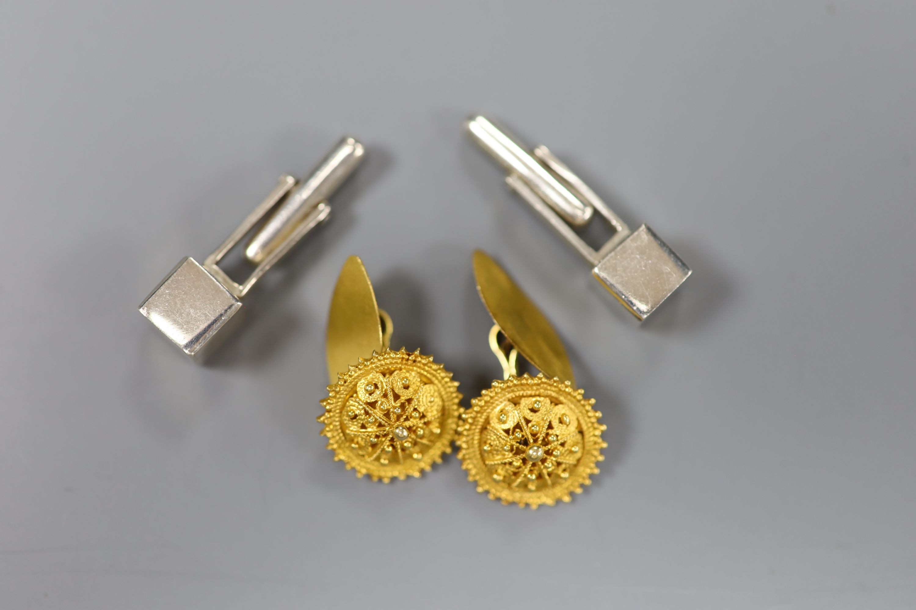 A pair of yellow metal cannetile work cufflinks, gross 6.8 grams and a pair of Peruvian Ilaria 950 white metal cufflinks.